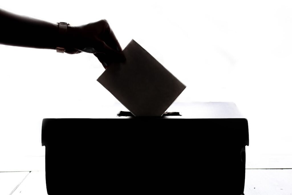 Person casting a vote into a ballot box