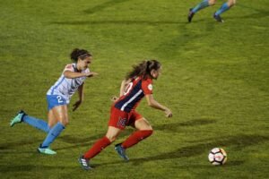 Women footballers challenging for the ball during a match